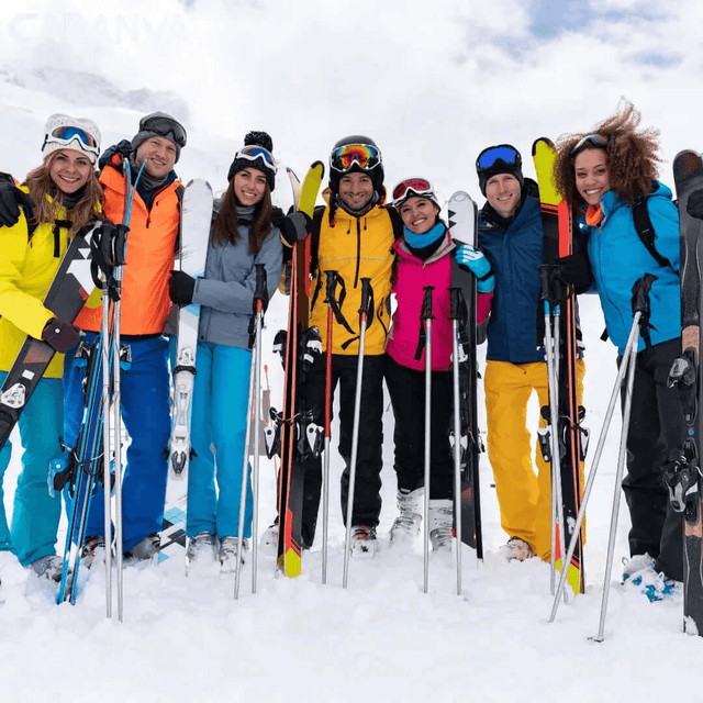 Grupo de amigos a sorrir na neve com os esquis e os bastões